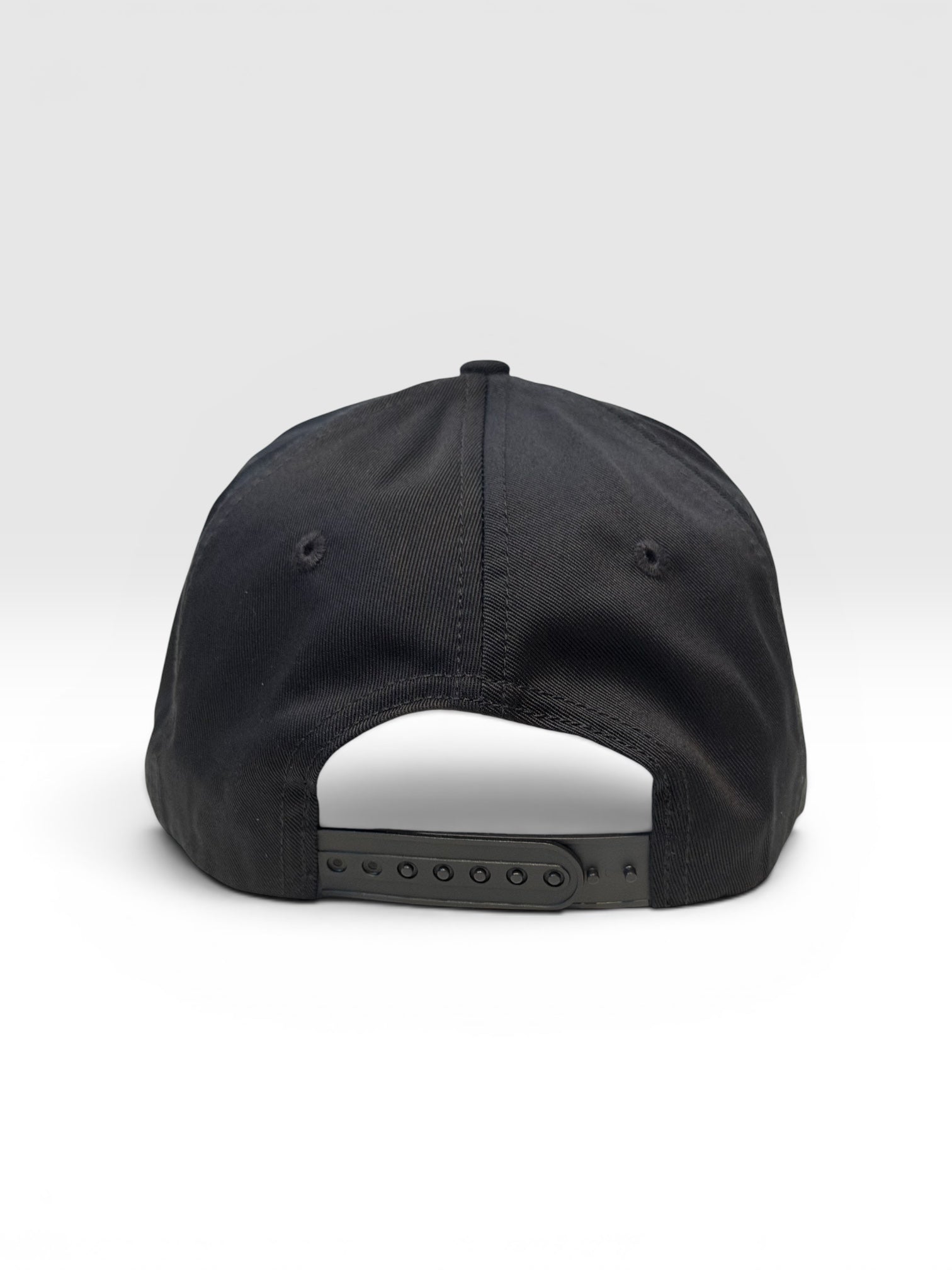 Back side of a black five panel snapback cap with a white background